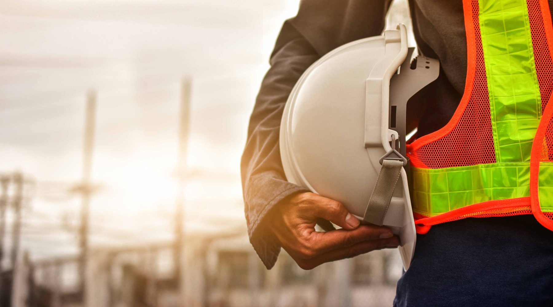 Field engineer holding a safety helmet at an industrial site